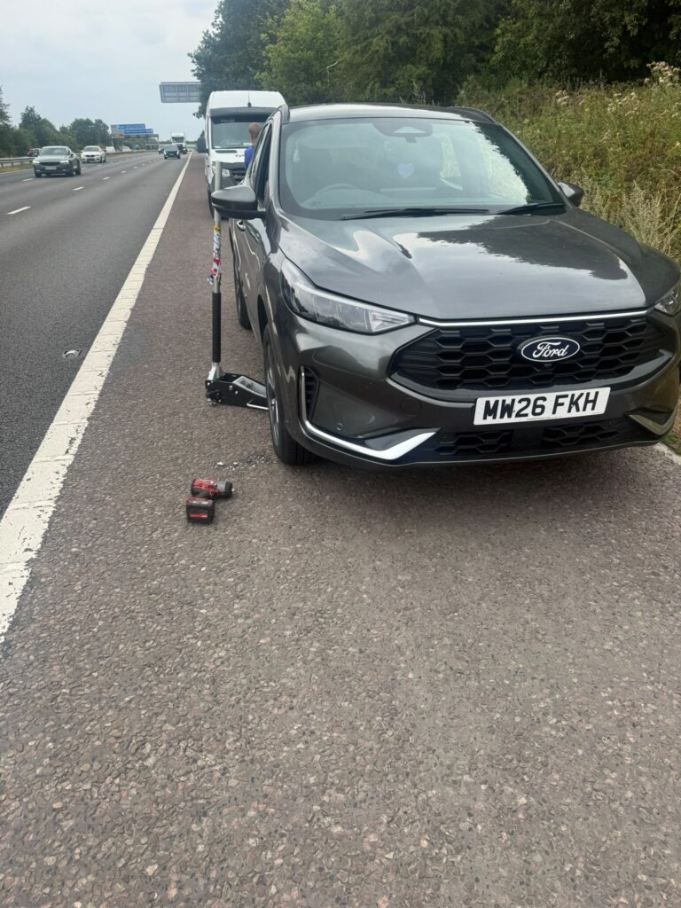 Ford car with a wheel removed during a roadside tyre call-out