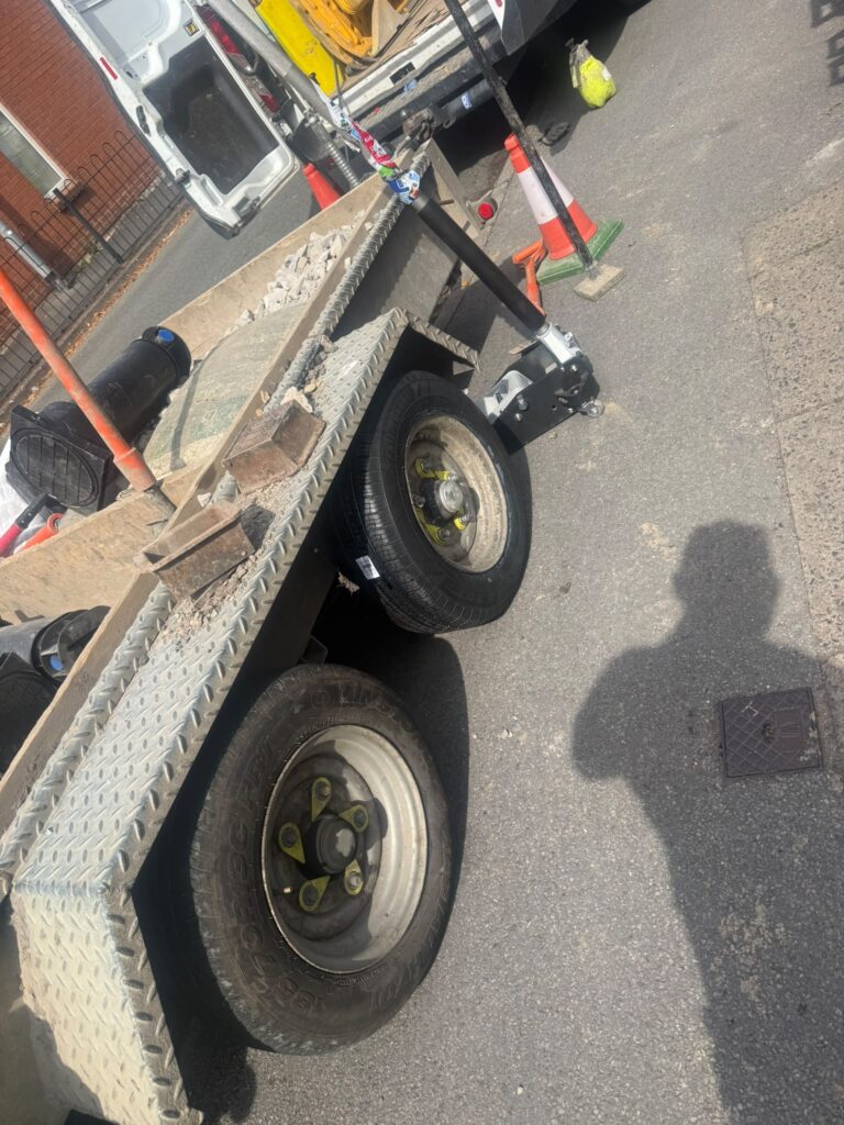 Twin-axle trailer with tyre fitting equipment beside its wheels